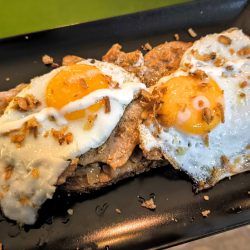 Rebanada de pan con cebolla <br>caramelizada, lomo plancha y huevos fritos